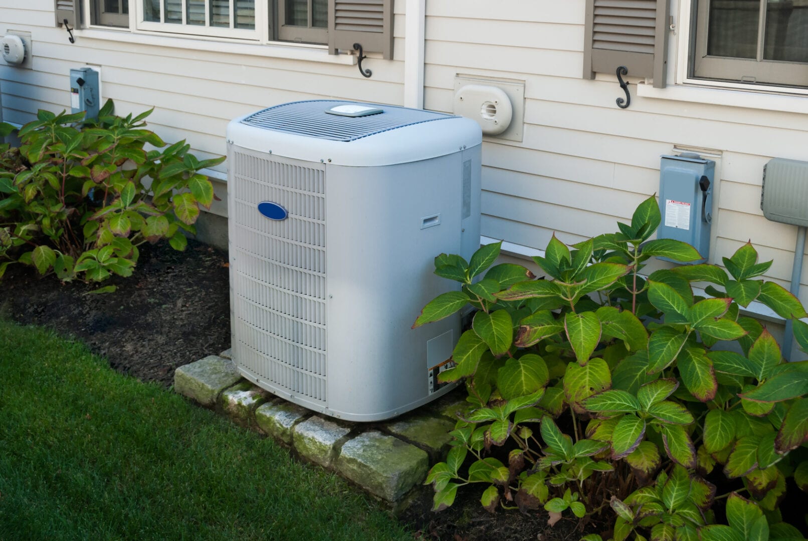 A residential air conditioner unit sitting outside of a house.